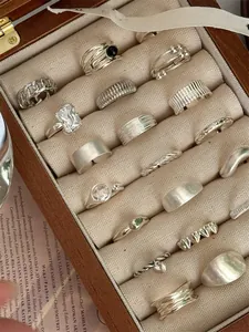 Macro view of assorted S925 sterling silver vintage rings in a wooden jewelry box.
