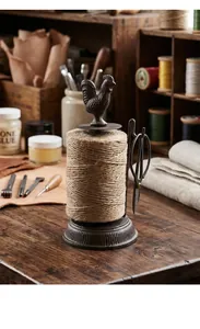 Vintage cast iron twine holder with rooster ornament and scissors on wooden workbench