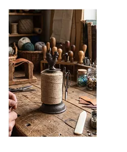 Vintage cast iron rooster twine holder dispenser with scissors on a rustic wooden desk