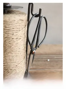 Macro detail of a vintage cast iron twine winder featuring an integrated scissor hook