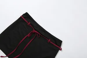 Détail en gros plan d'une mini-jupe noire avec une ceinture à nouer bordeaux