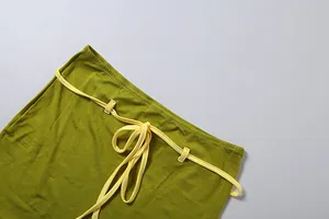 Détail d'une jupe moulante vert olive avec ceinture à cordon de serrage jaune