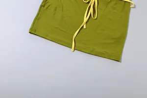 Détail de la texture et du cordon jaune de la mini-jupe moulante verte pour femme