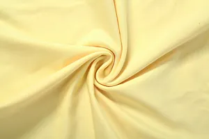 Gros plan montrant la texture douce et le drapé d'un tissu tricoté jaune clair.