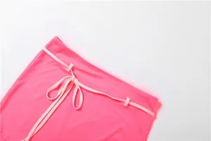 Gros plan détaillé d'une mini-jupe rose avec une taille à cordon de serrage contrastée.