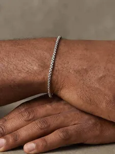 Détail d'un bracelet en maille vénitienne minimaliste en acier argenté sur un poignet