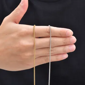 Collier chaîne box en acier inoxydable dorée et argentée présenté sur la main