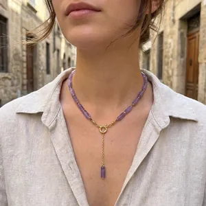 Detailed shot of an amethyst beaded necklace with a gold clasp on a model