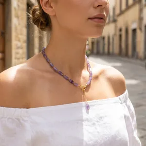 Detail view of a lavender amethyst beaded necklace with a gold clasp on a model.