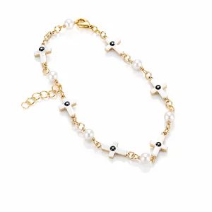 Detail of gold chain bracelet with white cross charms, pearls and lobster clasp