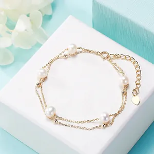 Nahaufnahme eines eleganten zweilagigen Goldkettchen-Armbands mit Süßwasserperlen