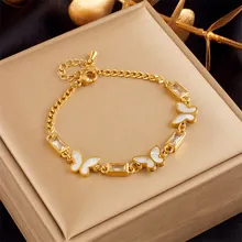 Detail of gold chain bracelet featuring white butterfly charms and rectangular zircon stones