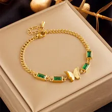 Detail of gold multilayer chain bracelet with green zircon stones and butterfly charm
