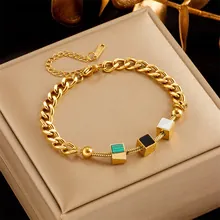 Detail of gold layered chain bracelet featuring green, black, and white cube charms