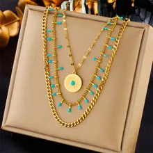 Detail of gold layered chain necklace with blue beads and a round coin pendant