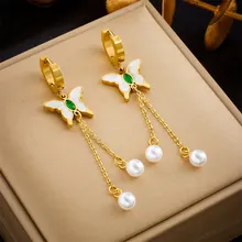 Macro shot of gold butterfly drop earrings with green gemstone and white pearls