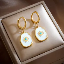 Macro detail of gold vintage hoop earrings with white enamel sun charms and turquoise beads