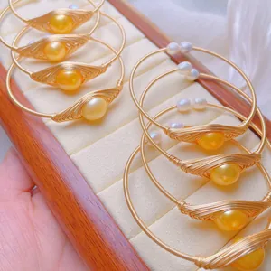 Macro detail of handmade 14K gold plated wire-wrapped bracelets with golden pearls