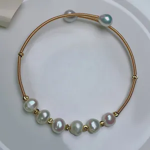 Detailed view of an adjustable 14K gold plated wire wrapped bracelet with freshwater pearls