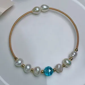 Detail view of 14K gold plated wire necklace with freshwater pearls and blue crystal