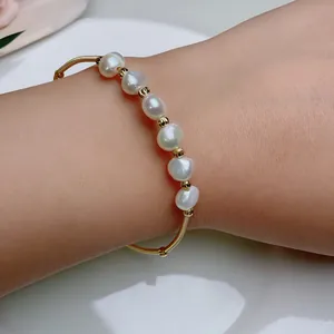 Detail of handmade wire wrapped freshwater pearl bracelet on wrist with gold beads