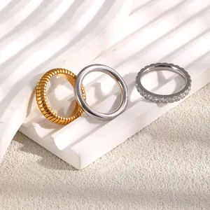Detailansicht von drei Edelstahlringen mit Goldbeschichtung, Streifen und Zirkonia-Kristallen.