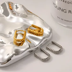 Close-up detail of vintage gold and silver twisted hoop earrings on a silver tray.