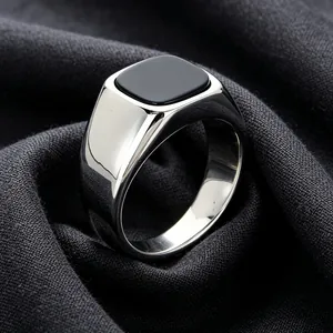 Close-up of a polished stainless steel signet ring featuring a square black onyx stone.