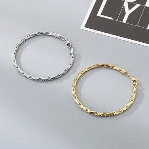 Vue détaillée de bracelets en acier inoxydable doré et argenté sur un fond gris neutre