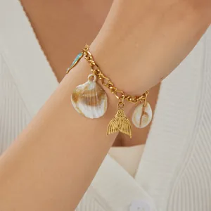 Detailed close-up of a gold-plated ocean charm bracelet with shell and mermaid tail