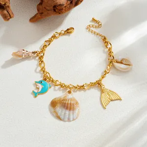 Detail of gold-plated ocean charm bracelet with dolphin, seashell, and fish tail pendants