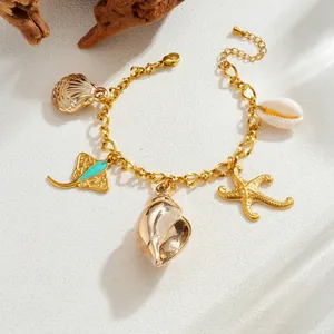 Detailed macro view of gold plated ocean charm bracelet with starfish and shell pendants.