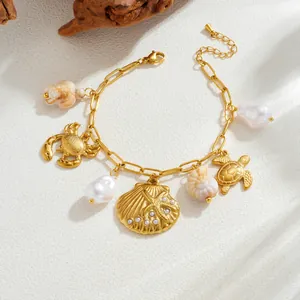 Close-up of gold-plated ocean charm bracelet with shell and pearl details