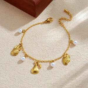 Detail view of gold-plated stainless steel bracelet with fruit charms and white pearls