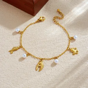 Close-up of gold plated stainless steel ocean charm bracelet with sea life charms and pearls