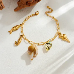 Detailed close-up of gold stainless steel bracelet featuring ocean-themed charms and shell