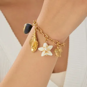Close-up detail of a gold-plated ocean charm bracelet featuring a turtle and shells. (81 chars)