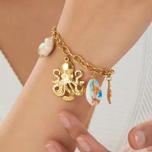 Close-up of gold-plated ocean charm bracelet featuring octopus and seashell designs.