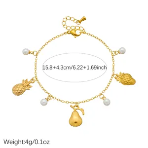 Detailed view of a gold-plated stainless steel charm bracelet with pearls and fruits