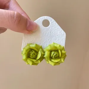 Macro detail of light green resin flower stud earrings with textured card
