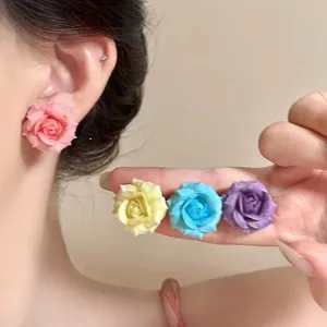 A detailed view of colorful resin rose earrings in pink yellow blue and purple