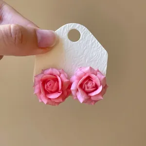 Detailed close-up view of pink resin rose flower stud earrings on a white card