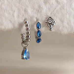 Primo piano di orecchini in acciaio con pietre blu a forma di marquise e a goccia