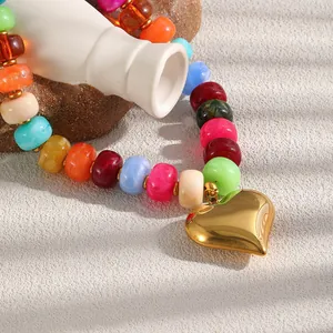 Dettaglio di una collana con perle in resina multicolore e ciondolo a cuore dorato