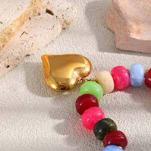 Primo piano del ciondolo a cuore dorato e delle perline in resina di una collana colorata