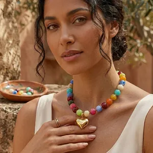 Dettaglio di una collana di perline in resina colorata con pendente a cuore dorato.