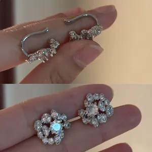 Close-up of 18K gold plated zirconia ear clips showing delicate floral and curved designs.