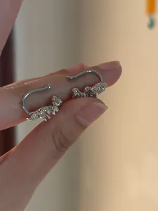 Detailed view of elegant 18K silver plated cubic zirconia ear cuffs held by hand