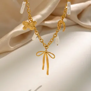 Close-up of 18K gold plated necklace with butterfly, bow, and baroque pearl charms