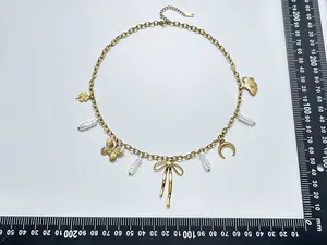 Gold stainless steel necklace with butterfly and pearl charms shown with a measuring ruler